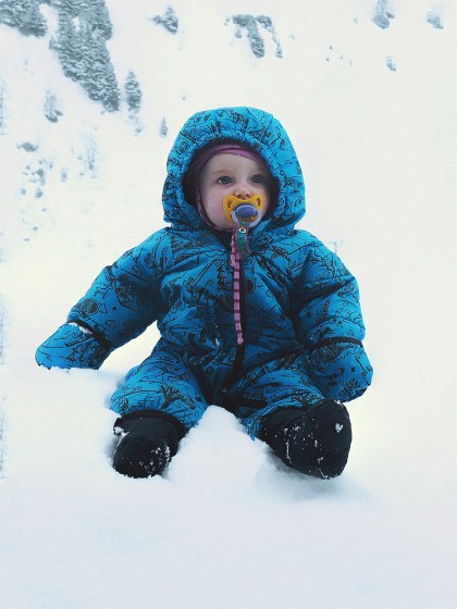Selbstversorgerhuette in der Schweiz. Baby sitzend im Schnee.