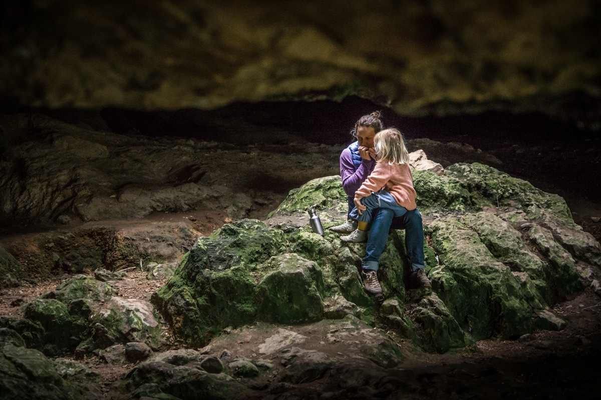 LIFE-for-FIVE-Grotte-Uruguay-GrutasDeSalamanca-Mama Tina sitzt mit ihrer Tochter auf dem Schoss in der Grotte und spielt Mundharmonika.